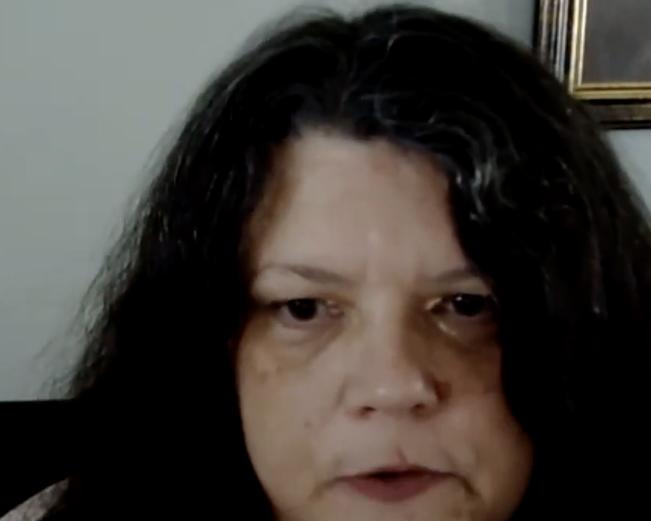 Corrina Hingley talks to a webcam. She has long dark hair.