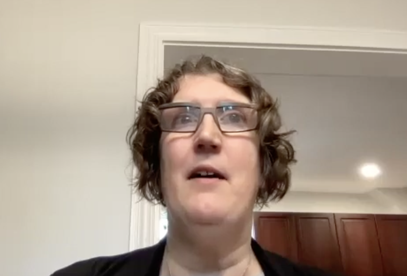 Jen Graham speaks in front of a webcam. She is a white woman wearing glasses and has short wavy hair.